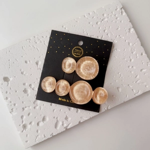 Detail of two cream resin hair clips with marble texture on a white stone display