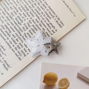 Detail view of y2k silver star hair clip with sequins on a book background