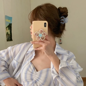 Pale blue translucent pumpkin claw clip holding a brown bun hairstyle in a mirror selfie