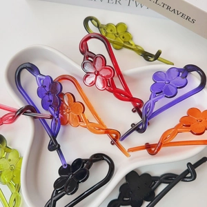 Flat lay of colorful acrylic flower hair clips in various vibrant shades on a tray