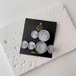 Detailed close-up of grey marble resin hair clips on a black handmade card display