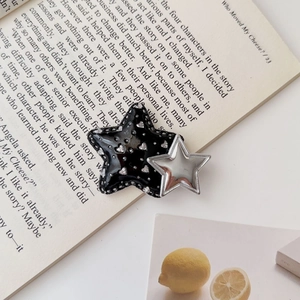 Detail of a y2k star hair clip featuring black glitter heart and silver metallic star layer