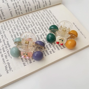 Detail of mini cherry hair claws with acrylic finish set on a vintage book page