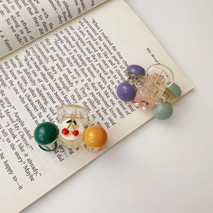 Detailed macro view of two cherry hair clips on a book page with colorful pearls