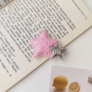 Detailed view of pink Y2K star hair clip with glitter print on aesthetic book background