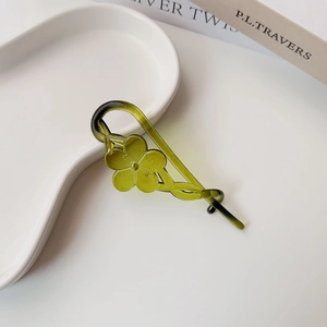 Detail of green floral resin hair clip with five-petal flower on a white ceramic tray
