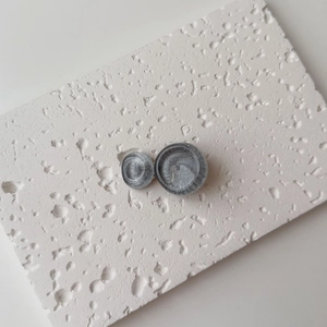 Macro shot of grey marble textured resin earrings on white stone display board