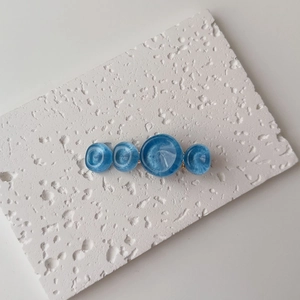 Detailed close-up of blue resin ocean-wave circles on a gold hair clip with pearly texture