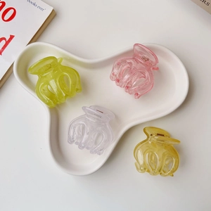 Close-up of translucent pumpkin-shaped hair claws in four pastel colors on a tray