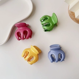 Close-up of four jelly candy color pumpkin hair claws in pink, green, yellow and purple