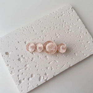 Detail showing high-gloss pink water-ripple resin circles on a gold-tone hair clip base