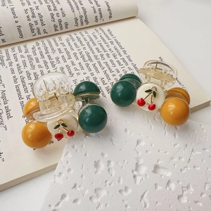 Detail of sweet cherry hair clips with green and yellow accents on an open book