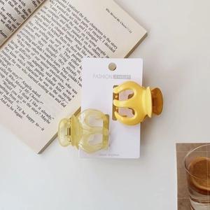 Detail showing two yellow jelly pumpkin hair claws on a fashion display card