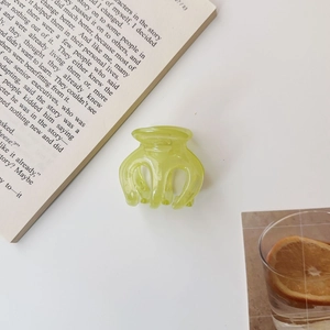 Detail of a translucent lime green mini hair claw clip in a refreshing lifestyle setting