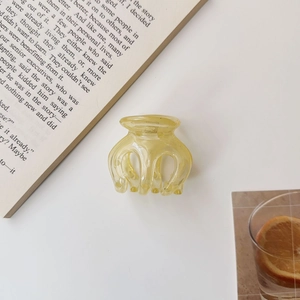 Detail of amber translucent pumpkin hair claw clip on a minimalist aesthetic background
