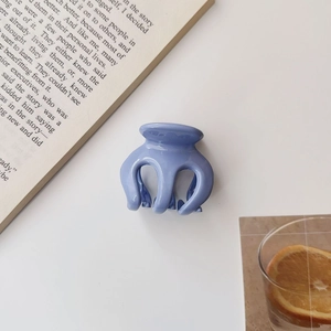 Close-up of a blue glossy pumpkin-shaped hair claw clip on an aesthetic book background