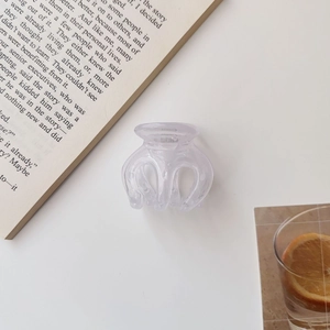 Close-up of a small light purple translucent jelly hair claw on an open book