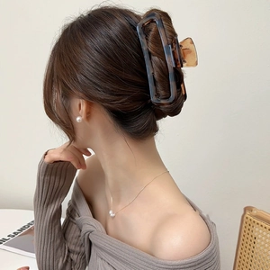 Large acrylic hair claw with blue marble texture worn by woman on long hair