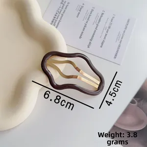 Dettaglio molletta per capelli ondulata marrone cioccolato con clip in metallo oro