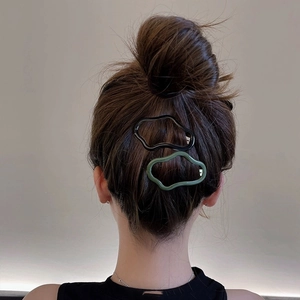Fermagli cavi a forma di nuvola neri e verde oliva indossati su una pettinatura a chignon