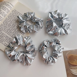 Dettaglio di quattro elastici argento metallizzato con texture in pelle e ampie pieghe