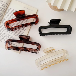 Set of four large acrylic hair claws in shell and champagne colors on an open book
