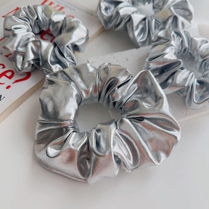 Set di quattro elastici argento metallizzato su marmo bianco e sfondo di rivista