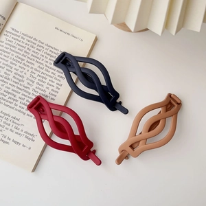 Three matte twist hair clips in navy blue, burgundy, and khaki on a white table