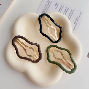 Dettaglio di fermagli per capelli ondulati in marrone scuro, nero e verde oliva su vassoio