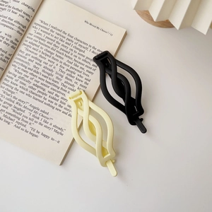 Close-up of matte black and cream twist hair claws on a book for elegant hair styling