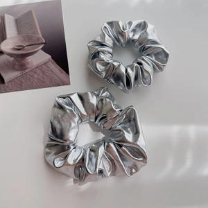 Primo piano di due elastici per capelli argento metallizzato con finitura lucida su bianco