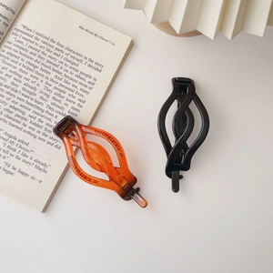 Close-up of black and amber matte twist hair clips on an aesthetic book background