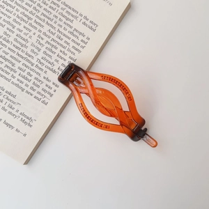 Detailed view of amber tortoiseshell hair clip with twisted hollow curve design