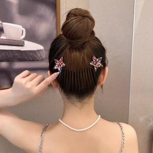 Dettaglio di due pettini a stella con strass colorati indossati su un'acconciatura chignon