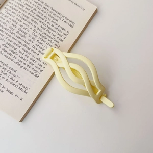 Close-up of matte cream twisted hair clip placed on a book showing smooth texture
