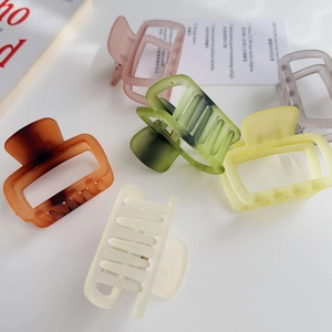 Close-up of matte square hair claw clips in six assorted jelly colors on a desk