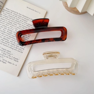Detailed view of large tortoiseshell and translucent acrylic hair claw clips on a book