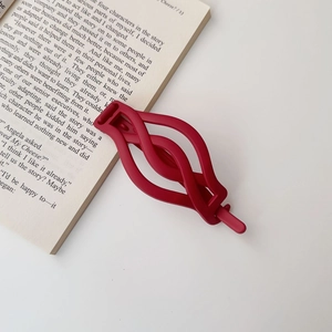 Close-up detail of a stylish matte red twist hair clip accessory for bun styling