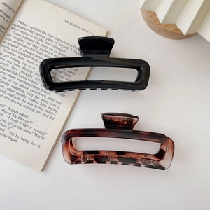 Detail shot of large acrylic hair claws in black and tortoiseshell on a desk