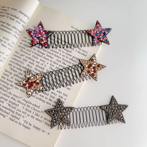 Set di tre pettini per capelli con stelle di strass posati su un libro aperto