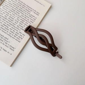 Close-up of matte dark brown hair clip with woven texture on a minimalist background