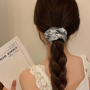 Elastico per capelli metallizzato argento per coda alta indossato da una modella