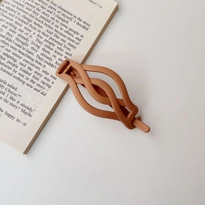 Detail view of a matte brown twist hair claw clip on an aesthetic book background