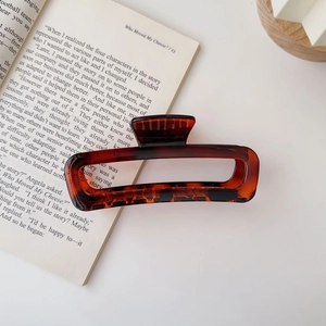 Close-up detail of a large amber tortoiseshell acrylic hair claw clip on a book