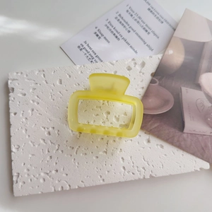 Detailed macro view of the pastel yellow matte hair claw clip with a hollow rectangle design