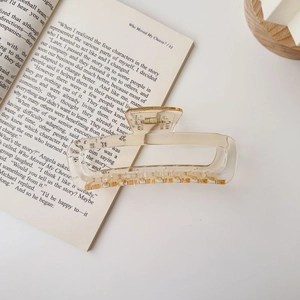 Detailed macro shot of a large transparent amber acrylic hair claw clip resting on an open book