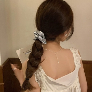 Scrunchie metallico argento su coda di cavallo bassa con estetica elegante e minima