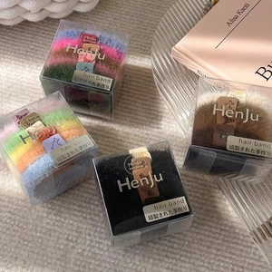 Lot de quatre chouchous en peluche dans des boîtes transparentes de couleurs variées