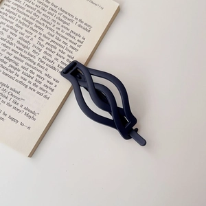 Detailed view of dark blue matte twist hair clip placed on an open book page