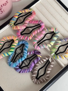 Detailed view of colorful knitted yarn wrapped metal hair clips in a jewelry box